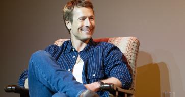 Glen Powell sits in an armchair during the Q&A portion of the screening event