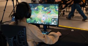 A view over the shoulder of a student playing a video game at a computer