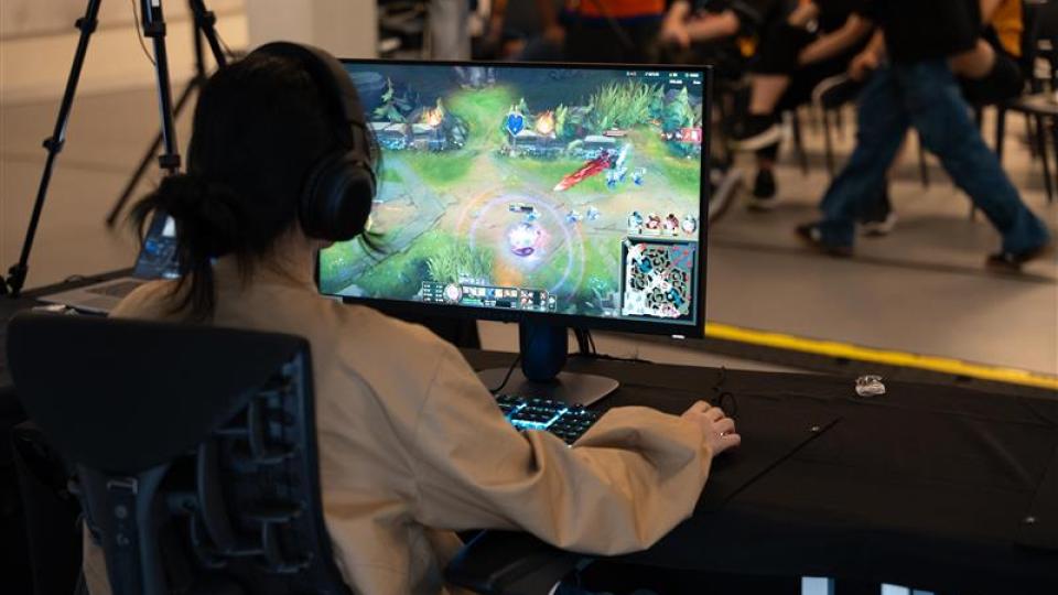 A view over the shoulder of a student playing a video game at a computer