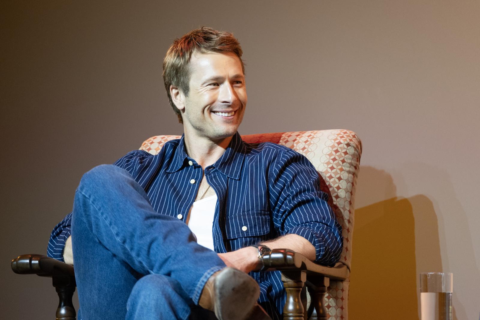Glen Powell sits in an armchair during the Q&A portion of the screening event