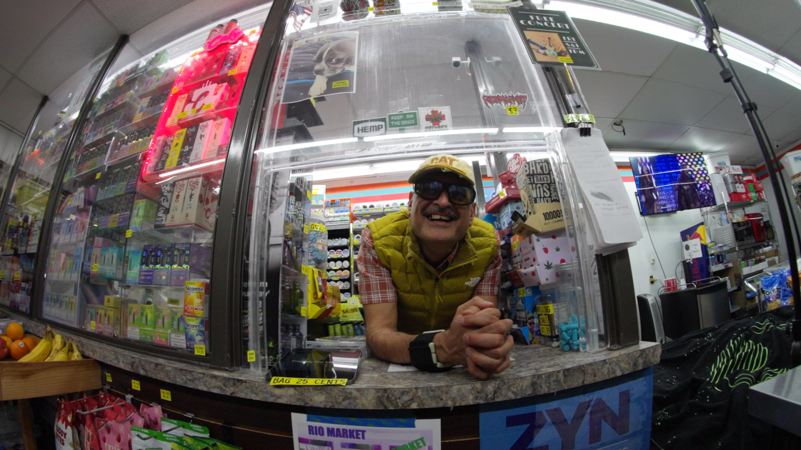 A still of Kai Hernandez's Film, "Rio Market" showing a man at a convenience store window through a fish-eye lens.