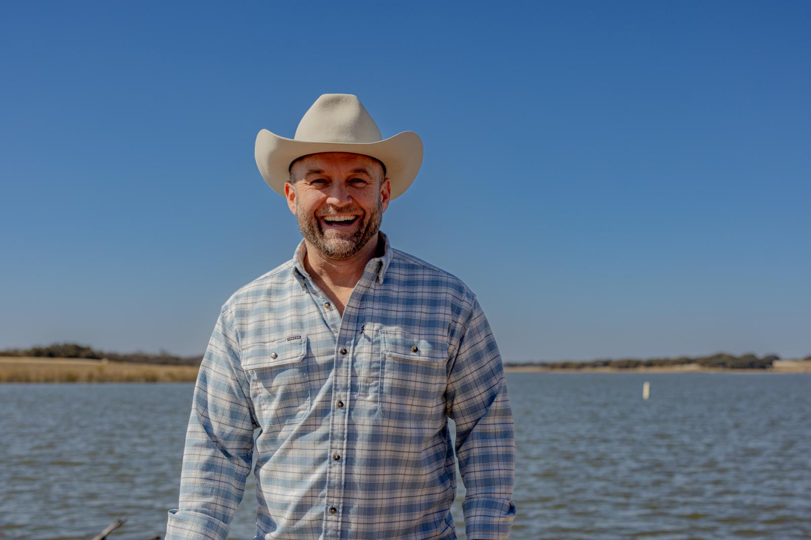 Chet Garner stands and smiles in front of a lake