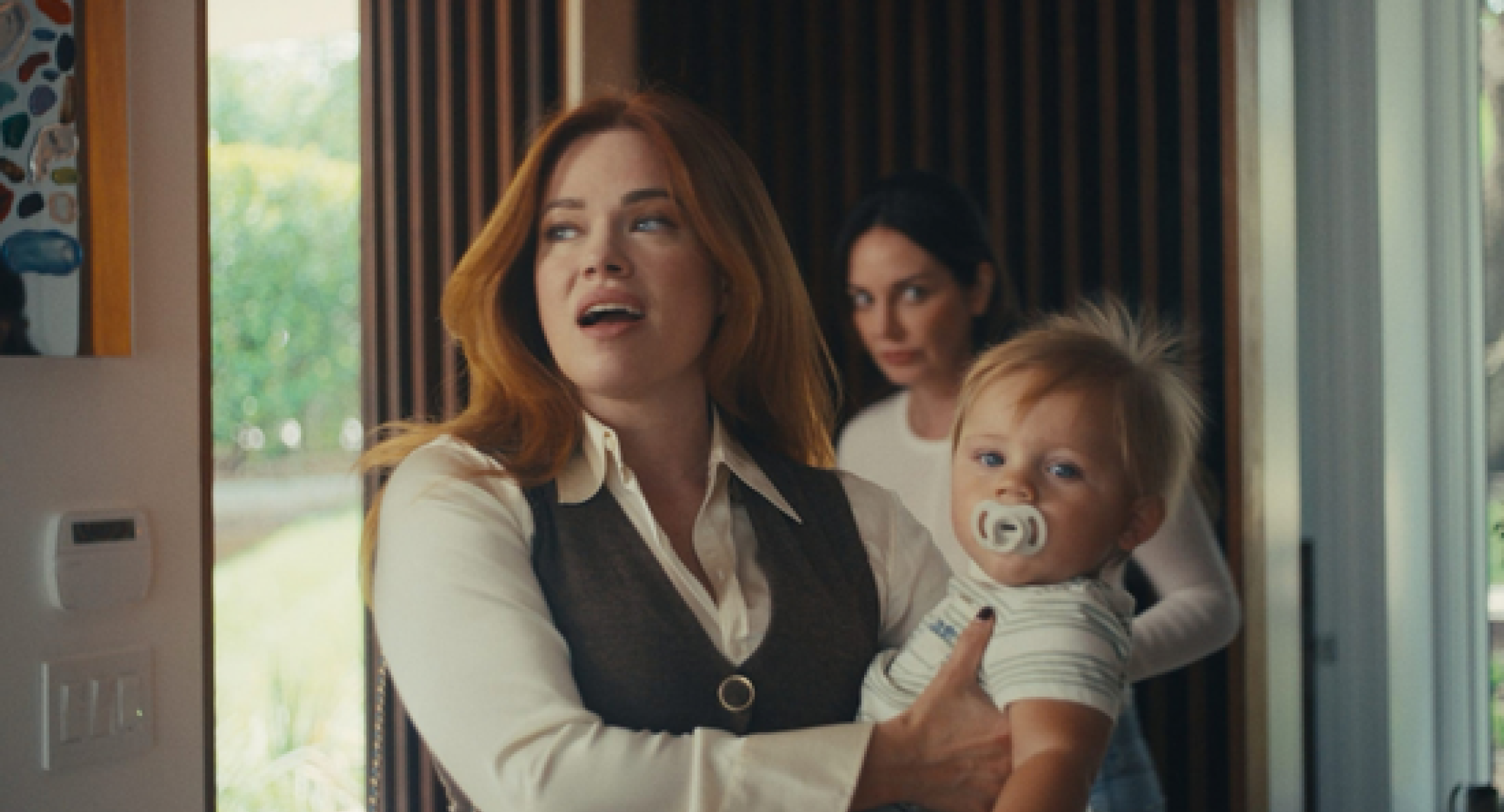 Screencap of the film "Anaimia". A woman holds a toddler. 
