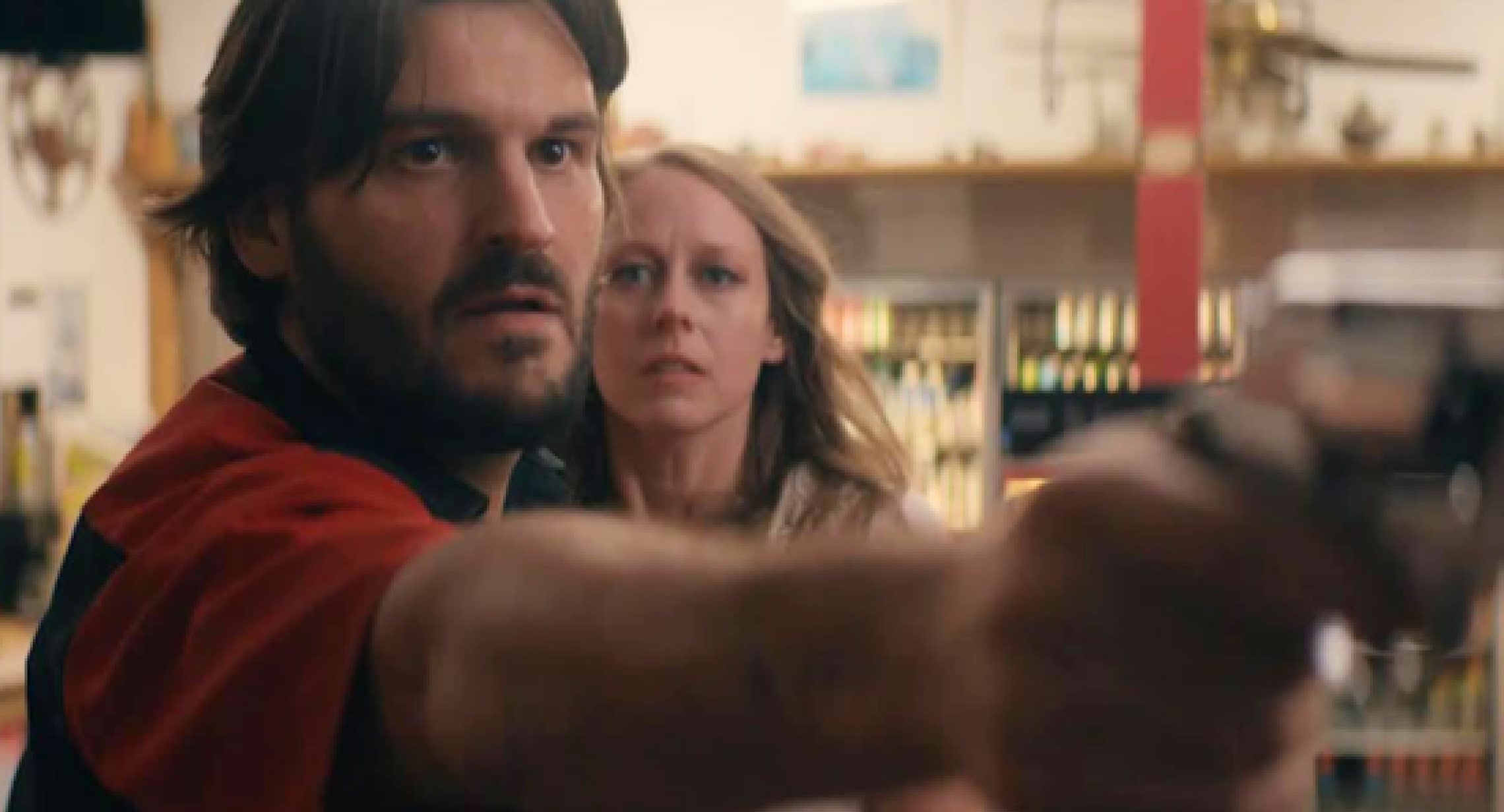 A screencap of the short film "Hitchhiker". A man holds a gun up toward someone outside the frame.