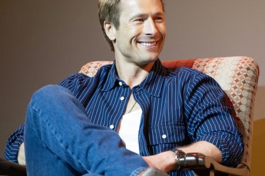 Glen Powell sits in an armchair during the Q&A portion of the screening event