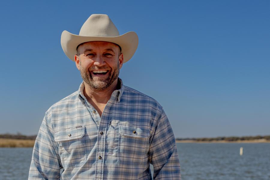 Chet Garner stands and smiles in front of a lake